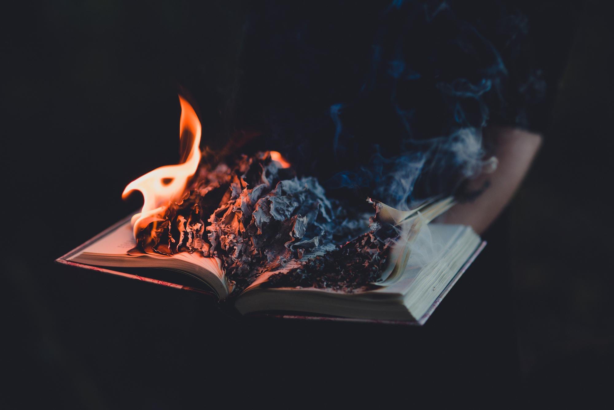 An open book where the open pages are slowly burning and turning to ashes.