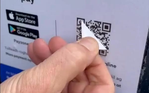 Close-up from video with someone peeling off a sticker with a fake QR code pasted on top of a valid QR code.